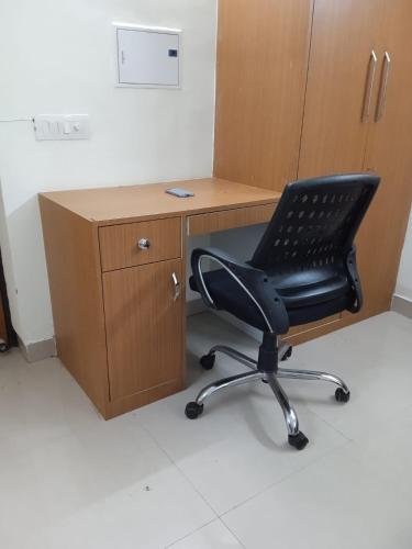 a black office chair sitting next to a wooden desk at Entire Studio Apt/Suite near Mall/Metro/ExpoMart in Noida