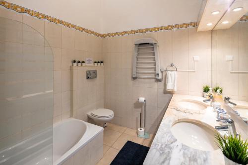 a bathroom with two sinks and a tub and a toilet at Casa Madrugada in Carvoeiro