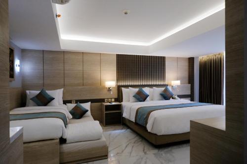 a hotel room with two beds and a desk at Dream of Aventus Hotel Kuta in Kuta