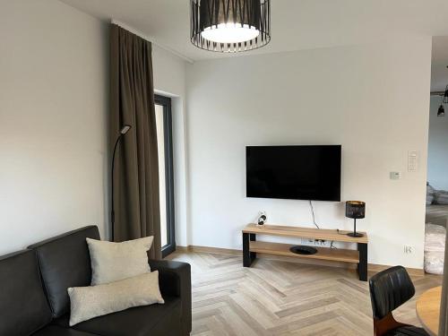 uma sala de estar com um sofá e uma televisão na parede em Ogrody Pieniawskie Apartamenty 37 em Polanica-Zdrój