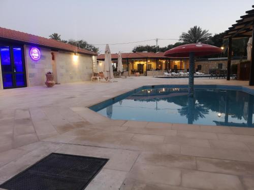 a swimming pool with an umbrella next to a building at Bab Al Shams Resort in Jericho