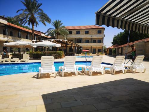 a group of white chairs and tables next to a pool at Bab Al Shams Resort in Jericho