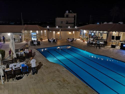 a swimming pool at night with people sitting at tables at Bab Al Shams Resort in Jericho