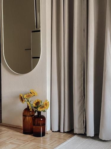 un jarrón con flores en el suelo junto a un espejo en Traunsee Design Apartment for 2 People en Gmunden
