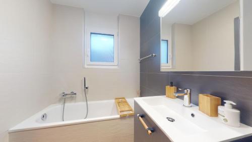 La salle de bains est pourvue d'un lavabo et d'une baignoire. dans l'établissement Spacious apartment - beautiful terrace with view, à Loèche-les-Bains