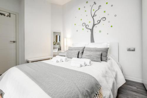 1 dormitorio con 1 cama blanca y un árbol en la pared en Apartamento en excelente ubicación, centro de Barcelona, en Barcelona