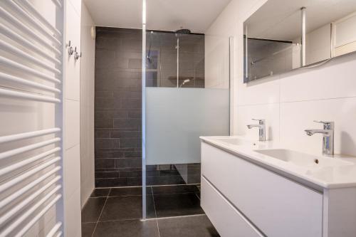 uma casa de banho branca com um lavatório e um chuveiro em Appartementencomplex Juliana 48 em De Koog