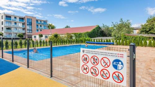 a swimming pool with a fence and tennis courts at Apartamenty Holiday City - Perłowa Przystań in Kołobrzeg