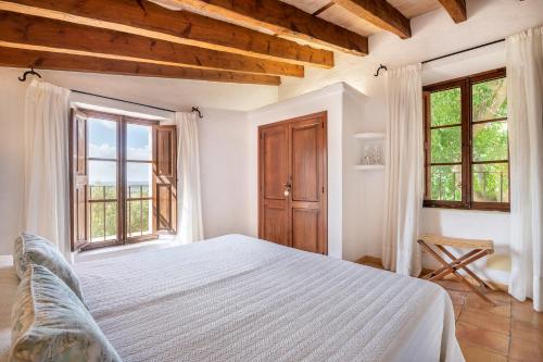 a bedroom with a white bed and two windows at Agroturismo Son Siurana in Alcudia