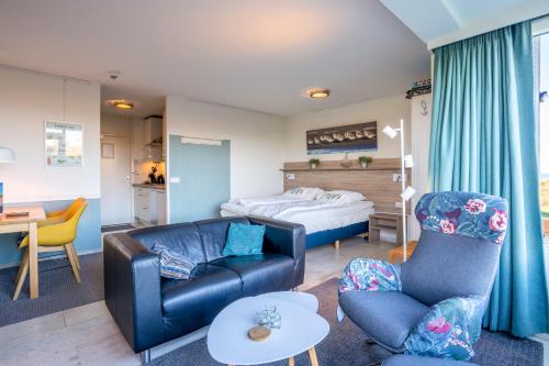 ein Wohnzimmer mit einem Sofa, Stühlen und einem Bett in der Unterkunft Appartementencomplex Juliana 68 in De Koog