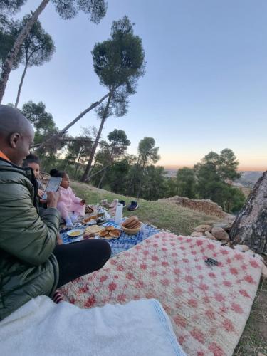 a man and two children sitting on a picnic blanket at L'oliveraie D'amizmiz in Amizmiz