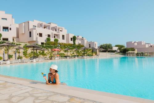uma mulher sentada na piscina de um resort em Basiliani - CDSHotels em Otranto