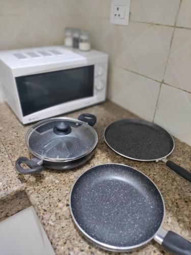 two frying pans on a counter with a toaster oven at Entire Studio Apt/Suite near Mall/Metro/ExpoMart in Noida