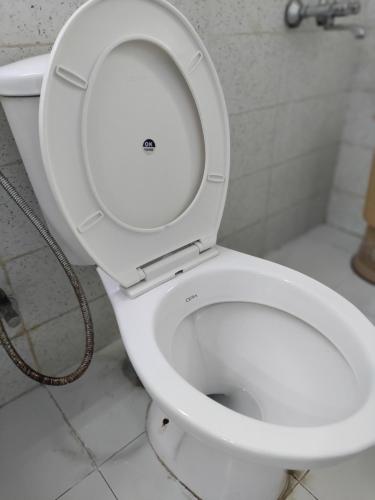 a white toilet with the seat up in a bathroom at Entire Studio Apt/Suite near Mall/Metro/ExpoMart in Noida