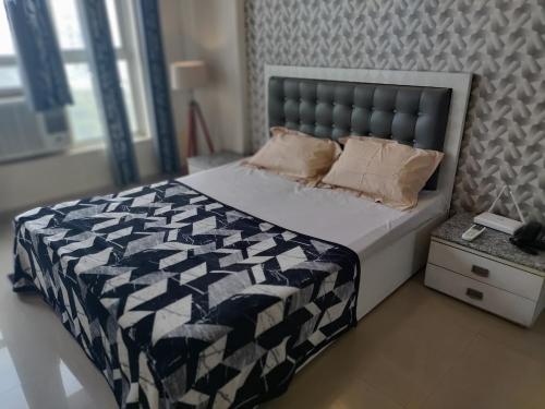 a bedroom with a bed with a black and white comforter at Entire Studio Apt/Suite near Mall/Metro/ExpoMart in Noida