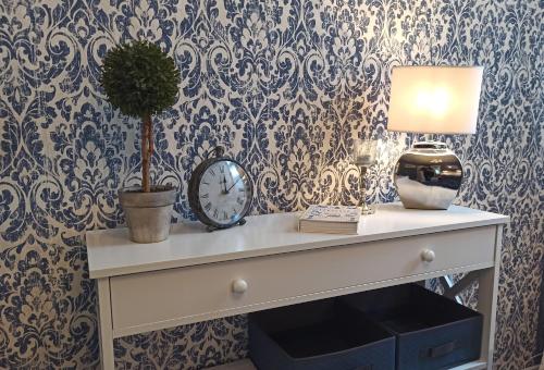 a table with a clock and a lamp and a plant at FeWo im Sahneröschen in Magdeburg