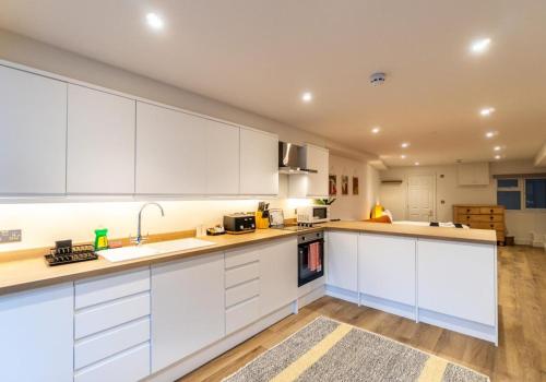 a large kitchen with white cabinets and wooden floors at The Narrow Studio By My Getaways in Brighton & Hove