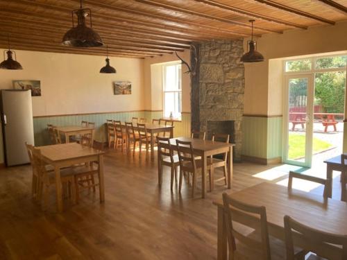 uma sala de jantar com mesas e cadeiras e uma lareira em Great Glen Hostel em Spean Bridge