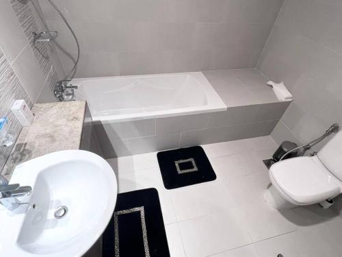 a bathroom with a sink and a toilet and a tub at SeaView Inn in Abu Dhabi