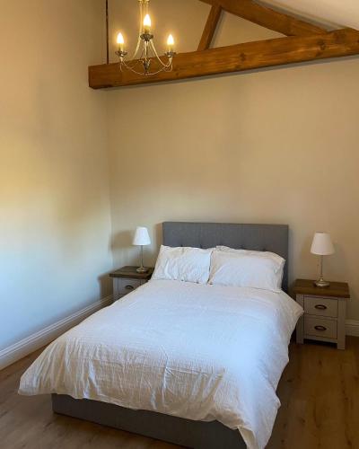 a bedroom with a large white bed with two night stands at Potcote farm stables accommodation fudges stable in Towcester