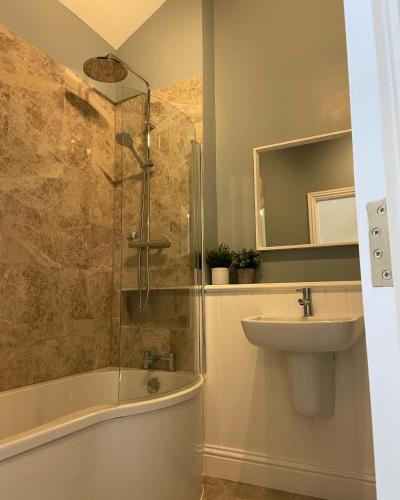 a bathroom with a shower and a sink and a tub at Potcote farm stables accommodation fudges stable in Towcester