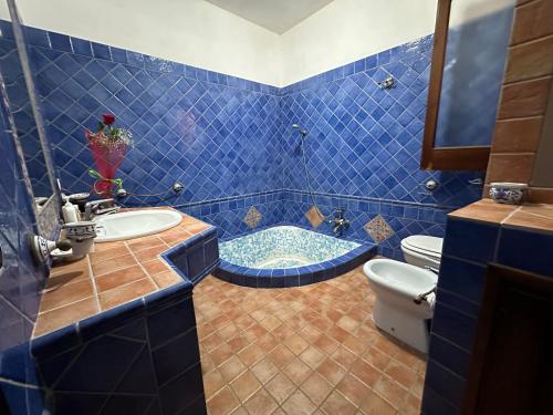baño de azulejos azules con bañera y aseo en Villa Dalila en Lampedusa