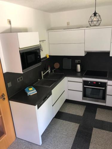 a kitchen with white cabinets and a sink and a microwave at Ferienwohnung Villa Hygge in Mitterteich