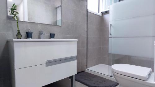 a white bathroom with a toilet and a sink at Dunas Beach II Apartment in Torrox Costa