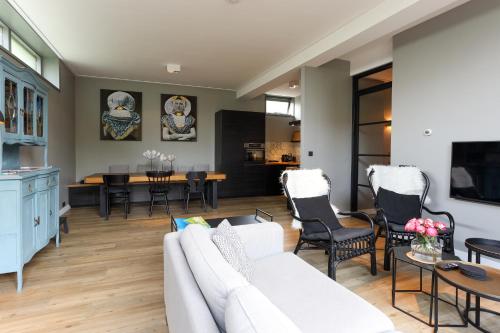 a living room with a white couch and chairs at ZEEenMEER stijlvol ruim vakantiehuis vlakbij strand Zeeland in Kamperland