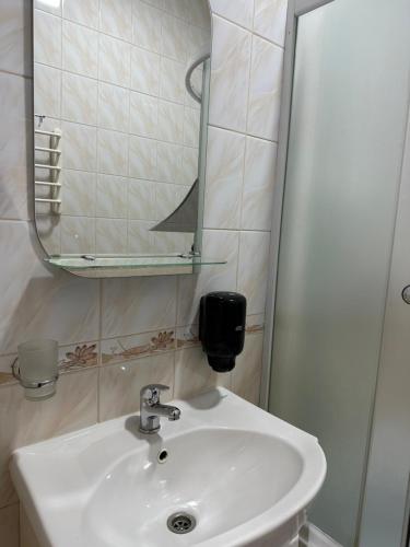 y baño con lavabo blanco y espejo. en Yunist, en Ivano-Frankivsk