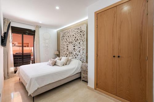 um quarto com uma cama e um grande armário de madeira em Precioso apartamento de planta baja en Las Salinas, Estepona em Estepona