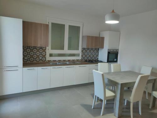 een keuken met witte kasten en een tafel en stoelen bij La casetta del Fico d'India in Marsala