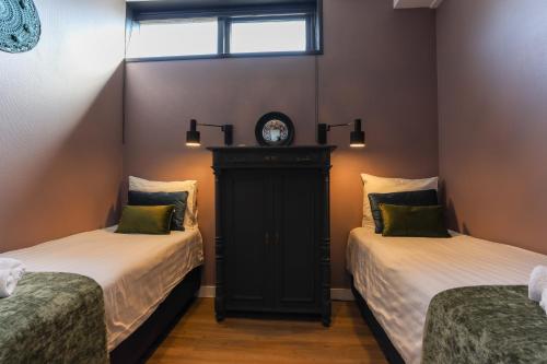 a room with two beds and a clock on the wall at ZEEenMEER stijlvol ruim vakantiehuis vlakbij strand Zeeland in Kamperland