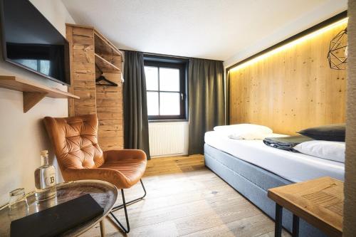 una camera d'albergo con letto e sedia di Berghotel Basur - Das Schihotel am Arlberg a Flirsch