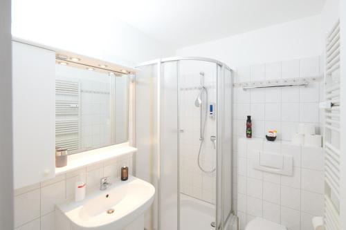 ein weißes Bad mit einer Dusche und einem Waschbecken in der Unterkunft Fernblick Hohegeiß Sauna/Hallenbad in Hohegeiß