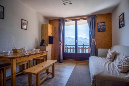 sala de estar con mesa, sofá y ventana en Studio with balcony and beautiful view - Alpe d'Huez - Welkeys en LʼHuez