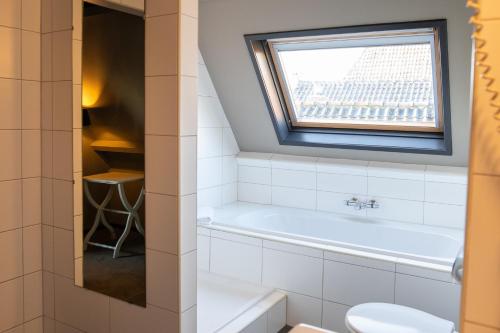 een badkamer met een bad, een toilet en een raam bij Yep! Slapen bij de Sluis in Blokzijl