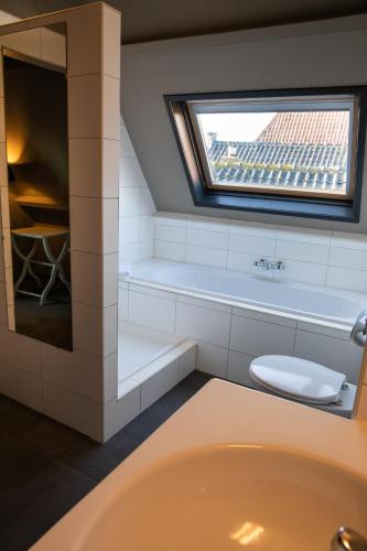 a bathroom with a tub and a toilet and a window at Yep! Slapen bij de Sluis in Blokzijl