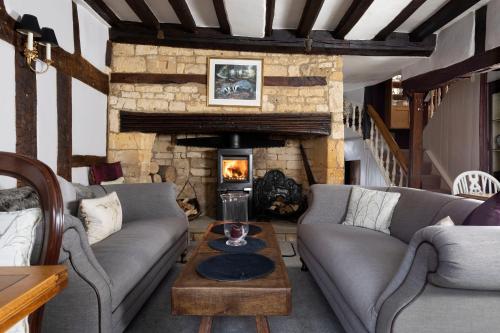 a living room with couches and a stone fireplace at Badgers Hall in Chipping Campden