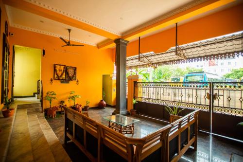 Habitación con paredes de color naranja, mesa y bancos en Sri Balaji Villas en Pondicherry