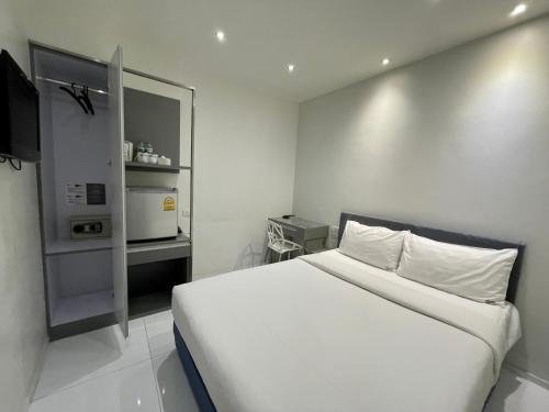 a white bedroom with a bed and a microwave at My Hotel Pratunam in Bangkok