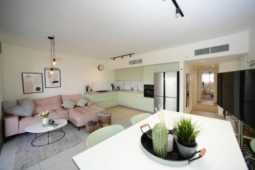 a living room with a pink couch and a kitchen at Gorgeous - Red rock and Sea view. in Eilat