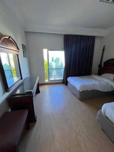 ein Hotelzimmer mit 2 Betten, einem Schreibtisch und einem Fenster in der Unterkunft Palm resort 2B in Sharm El Sheikh