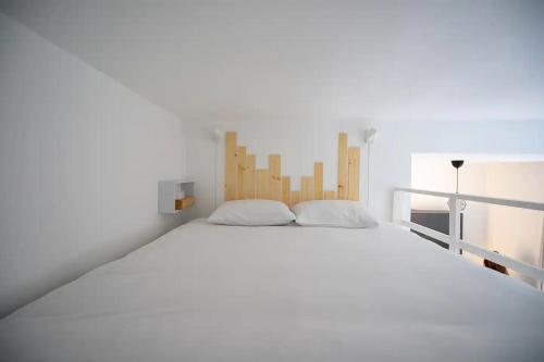 a white bedroom with a large white bed with wooden headboard at Marechal's Studio near train station & downtown in Nantes