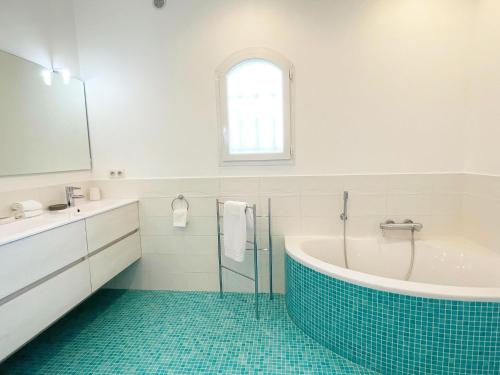 La salle de bains est pourvue d'une baignoire, d'un lavabo et d'un miroir. dans l'établissement Modern holiday home in Mougins with private pool, à Mougins