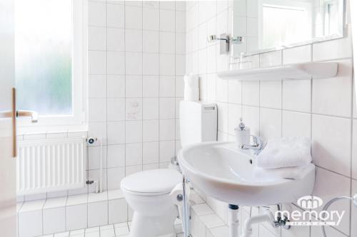 a white bathroom with a toilet and a sink at Memory Hotel in Braunlage