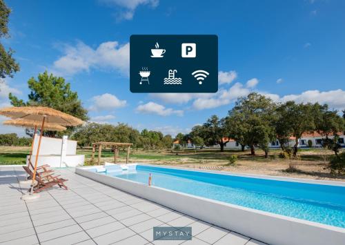 a swimming pool with an umbrella next to a resort at MyStay - Herdade do Vale da Abelheira in Grândola