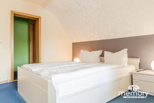 a white bed in a room with a green wall at Memory Hotel in Braunlage