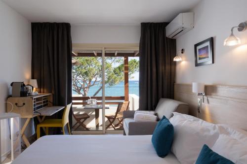 a hotel room with a bed and a view of the ocean at Hôtel La Roya in Saint-Florent