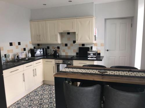 a kitchen with white cabinets and a table with chairs at Ulverston first floor apartment with roof terrace in Ulverston